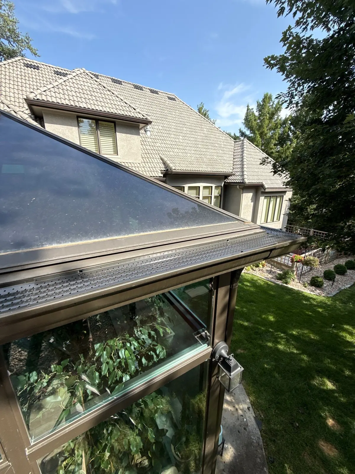 Completed gutter guards along a sunroom roofline