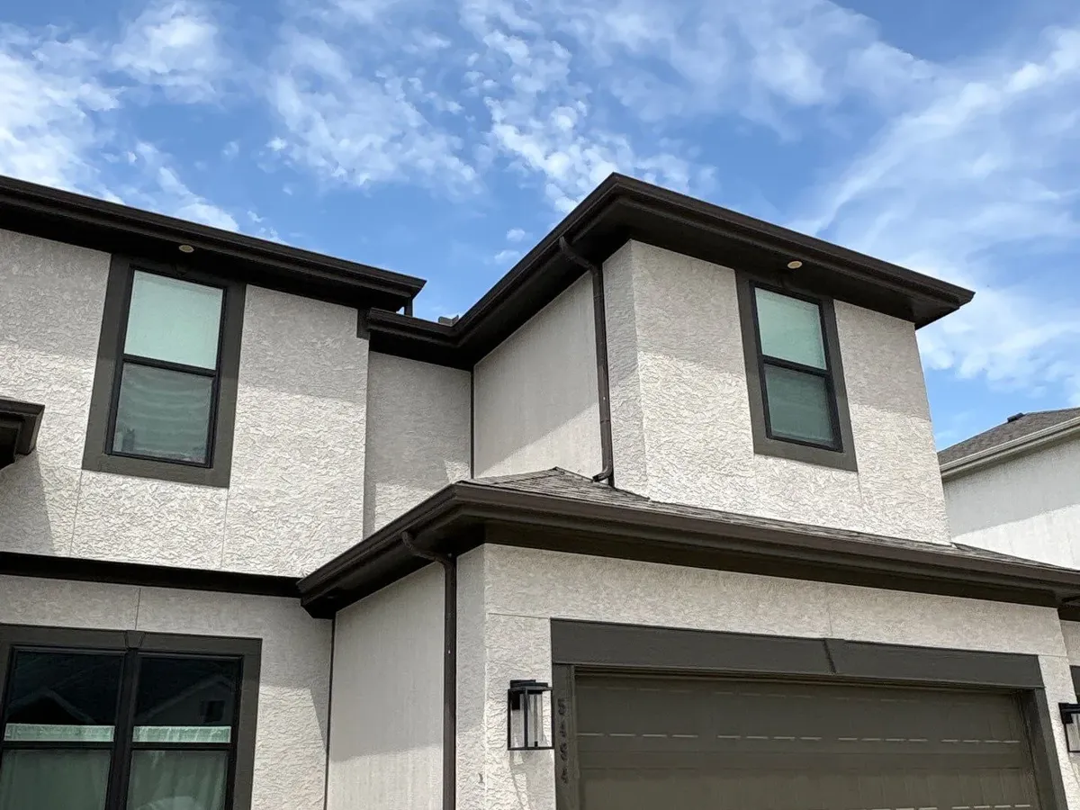 Dark seamless gutters on a two-story stucco home in Parkville, MO